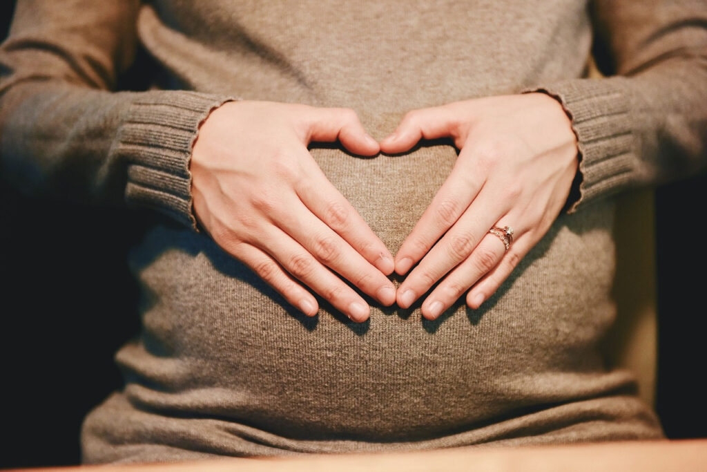 mujer poniendo las manos en forma de corazon sobre su barriga